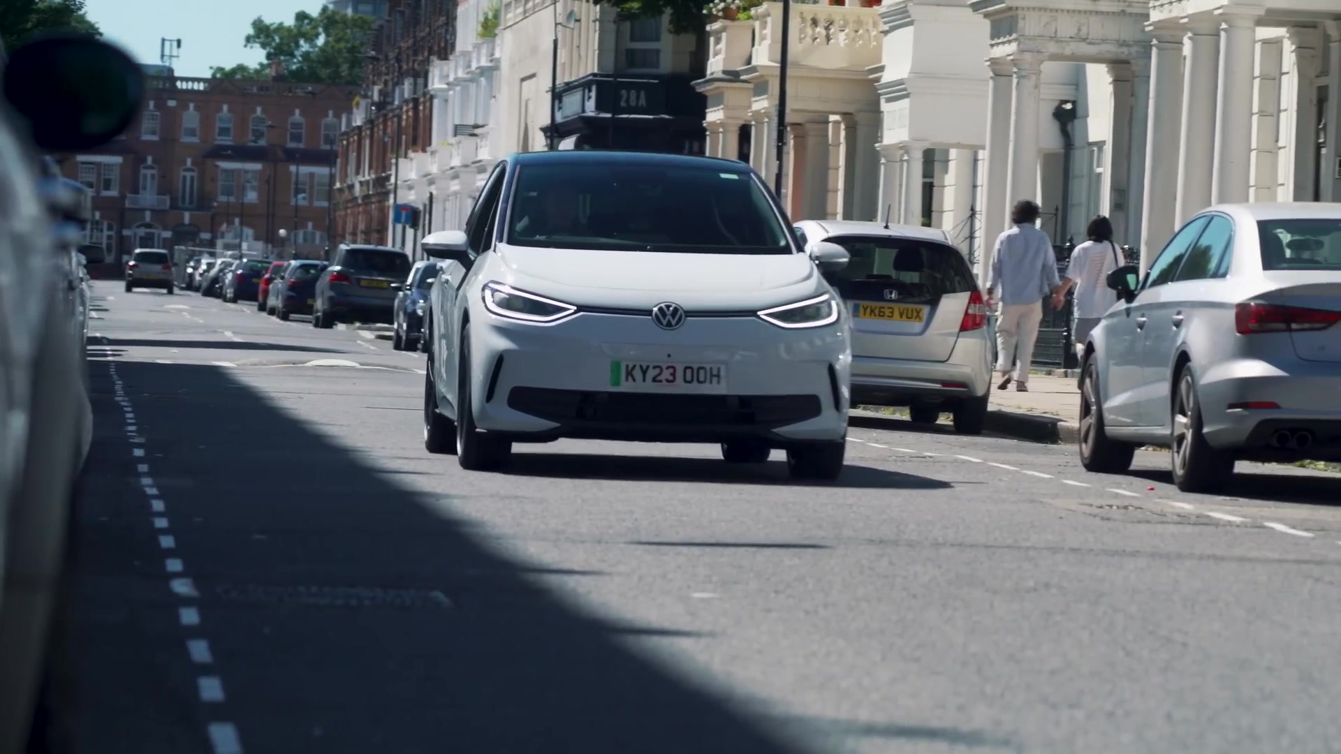 Witte Volkswagen ID.3 rijdt door een straat met geparkeerde auto's
